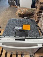 Top view of dishwasher showing control panel and attached hose on top covered with protective felt.