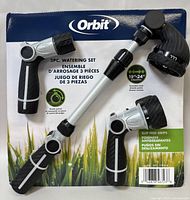 Photo of Orbit 3-piece watering set - hose sprayer gun, extension wand, and nozzle packaged on branded card with grass background.
