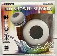 Front view of boxed 2Boom LED Bluetooth shower speaker, showing product and key features on packaging including suction, water resistance, built-in microphone and FM radio.