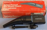 Front view of Micronta Enervac mini vacuum cleaner alongside original red box showing product name and features.