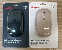 Two Staples wireless mice in original packaging, one black and one beige, with packaging indicating 2.4 GHz wireless technology.