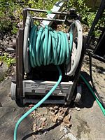 Front view of green hose wound on gray plastic hose reel cart with wheels