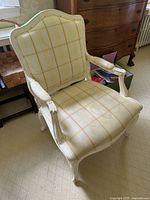 Front view of antique armchair with yellow plaid cushion and white wooden frame