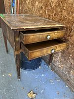 Front view showing the two drawers with distinctive cameo round handles open partially to show interior and the worn wood surface on top.