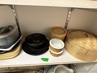 Shelf with bamboo steamer basket, wooden plate, and three small white bowls with woven holders.