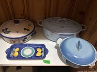 Photo showing two ceramic casserole pots with lids and a decorative ceramic tray with lemon design in front