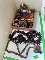Wide view showing two necklaces laid out below a box of assorted bangle bracelets.