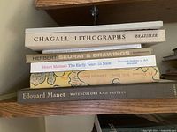 Shelf with five art books stacked horizontally, various titles and publishers visible