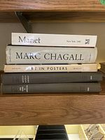First stack: Manet, Marc Chagall, Art in Posters, two dark art volumes (Munch, Rouault) on wooden shelf