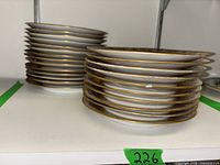 Stack of matching plates with gold trim, showcasing the multiple pieces in the set
