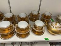 Front view showing teapot, cups and saucers arranged on shelf