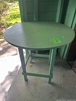 Photo of the green painted round wooden table showing the top surface and overall shape.