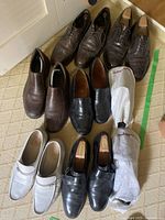 Photo of men's dress shoes in various brown, black, and white styles, most are leather, with some in cloth shoe bags