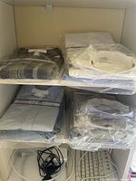 Top and middle shelf displaying neatly folded men's dress shirts in plastic packaging in various colors including gray plaid and white.