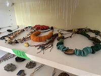 Top shelf display of various beaded stone and shell necklaces highlighting colors, textures, and styles.