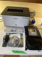 Overview of printer, cartridges, cables and mouse on table