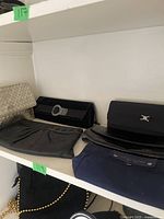 Photo showing five small clutches in various materials and colors on a shelf