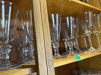 Shelf with multiple clear stemmed glasses of varying heights and shapes