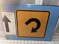 Front view of framed wall art showing U-turn sign motif on yellow square with arrow print on adjacent panel