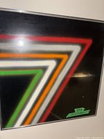Front view of framed abstract neon triangle wall art showing colored stripes and aluminum frame