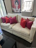 Front view of white silk fabric couch showing stripe pattern and red cushions