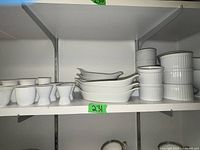 Photo showing white porcelain ramekins, serving dishes, and bowls arranged on a shelf.