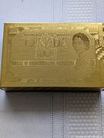 Gold embossed box resembling Canadian 1000 dollar bill design, housing the cards.