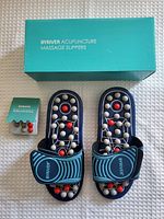 Top view of Byriver slippers showing adjustable straps, massage nodes, and extra nodes with manual beside the box.