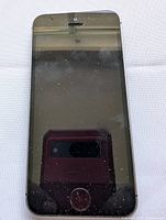 Front view of iPhone SE showing black screen with smudges and reflection of camera.