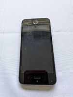 Front view of original Apple iPhone SE showing screen with home button, visible smudges and dust