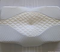 Top view of the cervical support pillow showing quilting and contoured shape with central raised area.