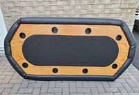 Top-down view of the poker table showing wood-like surface, black central play area, and eight cup holders around padded vinyl edge.