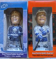 Front view of two Toronto Maple Leafs bobblehead dolls in original boxes, showing detail of Darryl Sittler in blue jersey and Tie Domi in white jersey, hand painted.