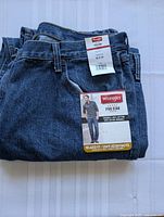 Folded Wrangler jeans showing front with tags indicating size 42x32 and model Five Star.