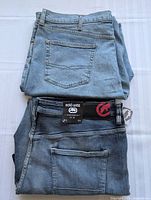 Stack of two pairs of men's denim jeans, one shorts and one full length, folded