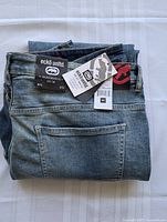 Folded men's jeans showing brand Ecko Unltd. tags, size 40, and back pocket detail
