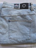 Close-up photo of back pocket and Airwalk brand patches on waistband of light blue men's jeans.