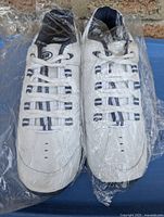 Pair of men's white and blue running sneakers, size 13, wrapped in plastic showing overall new condition with minimal discoloration on one shoe's sole.
