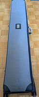 Closed black padded carrying case with handle, rectangular shape, gray stitching, and label pocket on one side, approximately over 6.5 ft long.