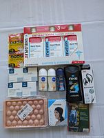 Full view of lot items arranged on white background: antibacterial hand wash packs, deodorants, body wash, earphones, pet chews, hand warmers, tapes, ice trays, headphones and poncho.