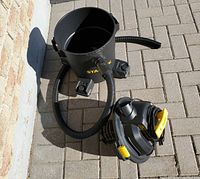 Stanley wet dry vacuum parts including main tank unit and detached hose shown outdoors on paving.