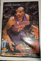 Photo of framed poster depicting Vince Carter in a Toronto Raptors jersey dribbling a basketball, displaying a Gatorade logo and a black autograph at bottom right.
