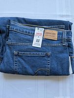 Folded blue denim jeans with visible Levi's Signature leather patch and attached tags.