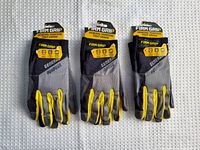 Three pairs of Firm Grip gloves shown front view with yellow detailing on fingers, grey and black fabric body, with tags attached indicating new condition and size XL.
