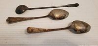 Three vintage silverplate utensils displayed on a white surface, showing front view indicating condition and design detail.