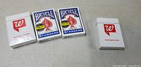 Four decks of new playing cards on a flat surface: two Bicycle Standard decks, two Walgreens decks