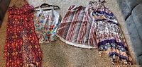 Four multicolored sun dresses laid out on carpet, visible color and pattern details clear