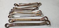 Nine assorted boxed end wrenches laid flat, showing front side with surface rust and markings.