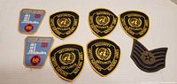 Nine assorted patches including United Nations Security and blue UN emblem patches along with a chevron patch.