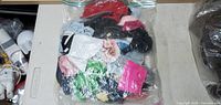Clear resealable plastic bag filled with assorted doll clothing items of various colors and styles